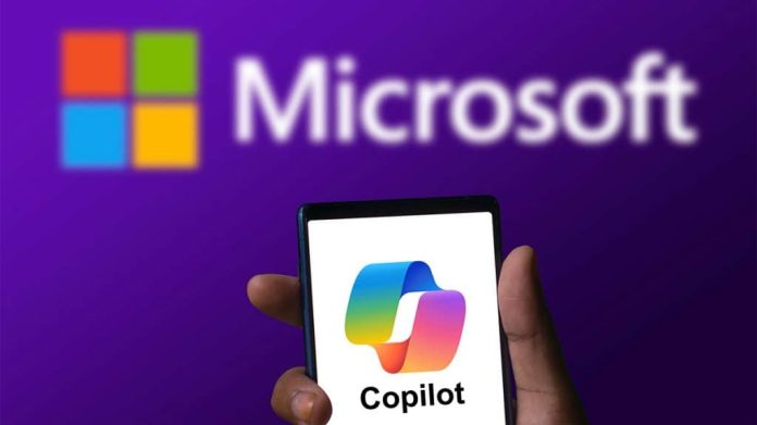 Pessoa segurando celular com logotipo do Copilot na tela e, ao fundo, está a logomarca da Microsoft