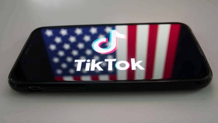 Logo do TikTok em um smartphone com a bandeira dos EUA de fundo