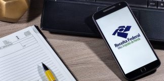 Receita Federal - Meu imposto de Renda (Brazilian Federal Revenue Department) logo on smartphone screen on office desk. Income tax declaration in Brazil
