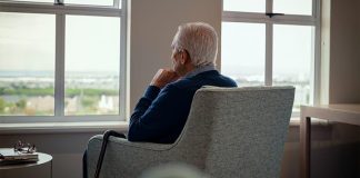 Idoso com Alzheimer sentado em poltrona olhando para janela