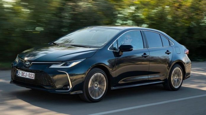 imagem mostra um carro preto (Toyota Corolla 2024) andando em uma rodovia
