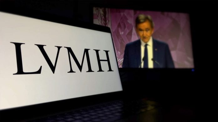 Celular com logotipo da Louis Vuitton na tela e, ao fundo, imagem de Bernard Arnault