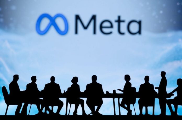 Ao fundo, em um telão e meio desfocado, logo da Meta; à frente, sombras de várias pessoas sentadas em uma mesa