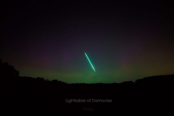 Meteoro bola de fogo cruza o céu colorido pela aurora