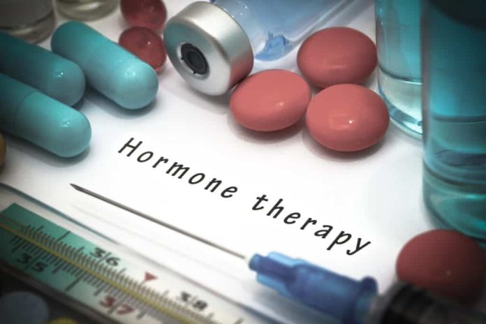 imagem mostra o nome "terapia hormonal" em inglês em um papel que repousa sobre uma mesa, rodeado por seringa com agulha e medicações