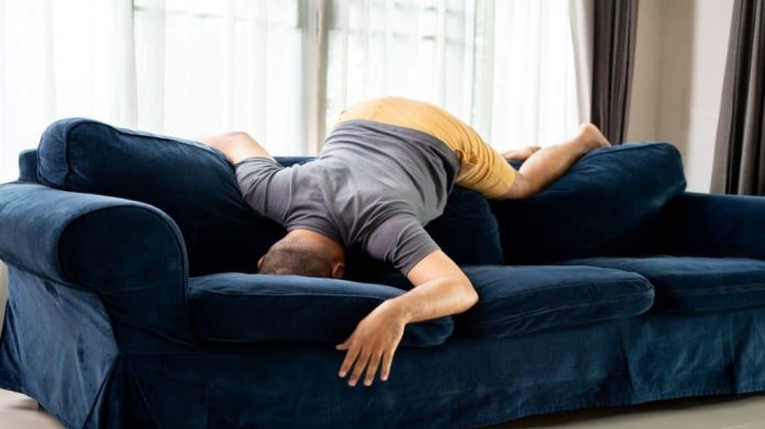 Pessoas engraçadas e embriagadas com ressaca descansando no sofá depois da festa. Homem asiático infeliz com dor de cabeça, chateado e frustrado com problemas de amor, sentindo desespero e ansiedade. Homem asiático deprimido e estressado.