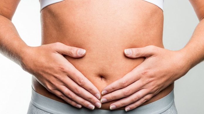 Mulher com as duas mãos sobre a barriga na região do útero e do intestino