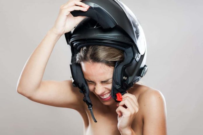Imagem mostra mulher tentando retirar o capacete que está apertado