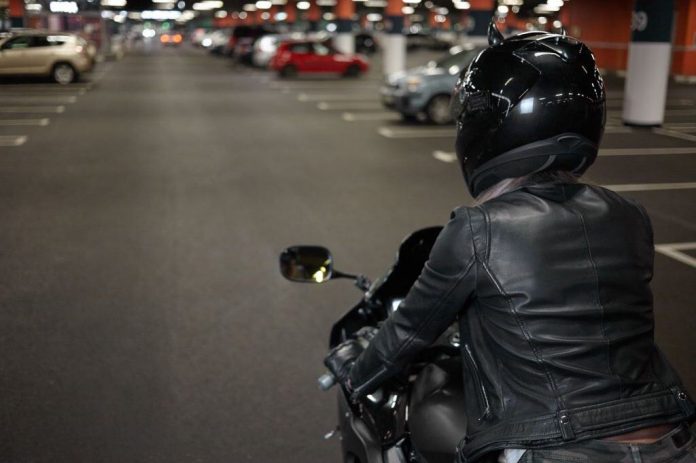 Mulher pilotando moto em estacionamento (Imagem: 